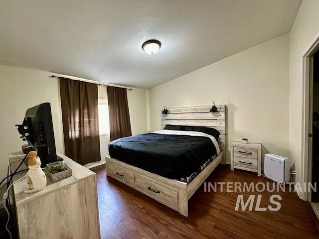 bedroom with a textured ceiling and dark hardwood / wood-style flooring