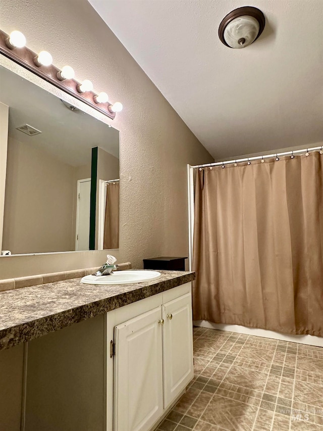 bathroom featuring vanity, vaulted ceiling, and a shower with curtain