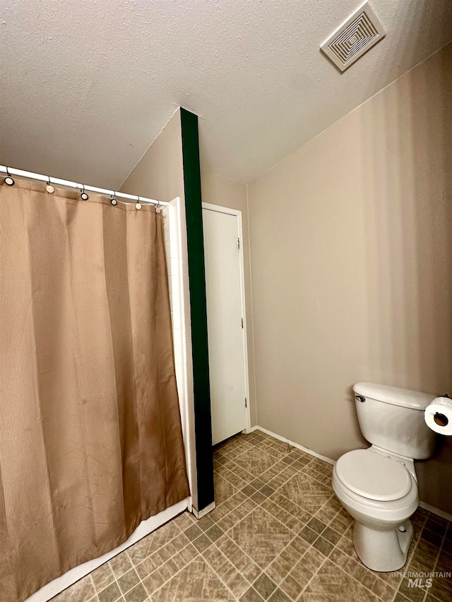 bathroom featuring toilet, a textured ceiling, and walk in shower