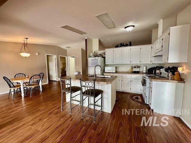 kitchen featuring custom exhaust hood, white cabinetry, a kitchen island with sink, and white appliances