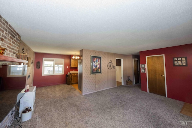 unfurnished living room with a textured ceiling, a chandelier, and carpet