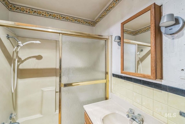 bathroom featuring decorative backsplash, vanity, and combined bath / shower with glass door