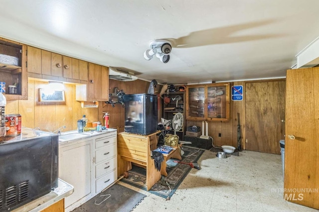 kitchen featuring white cabinets, wooden walls, and sink