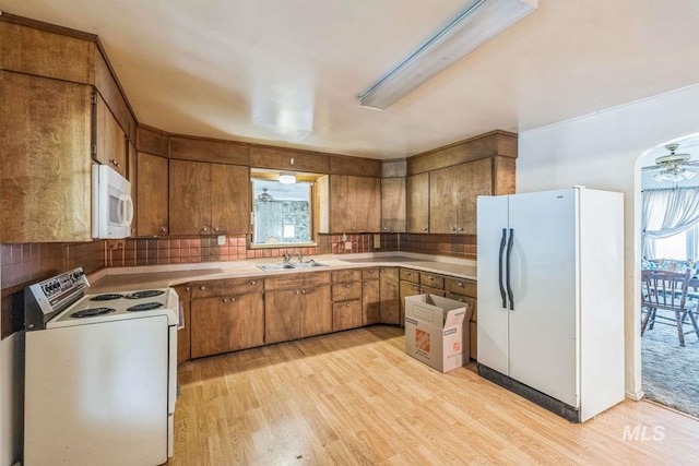 kitchen with decorative backsplash, white appliances, ceiling fan, sink, and light hardwood / wood-style flooring