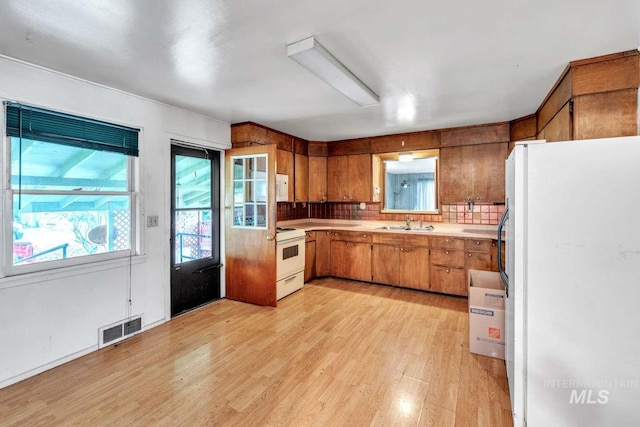 kitchen featuring tasteful backsplash, sink, light hardwood / wood-style floors, and white appliances