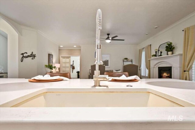 ensuite bathroom featuring recessed lighting, crown molding, a lit fireplace, and ceiling fan