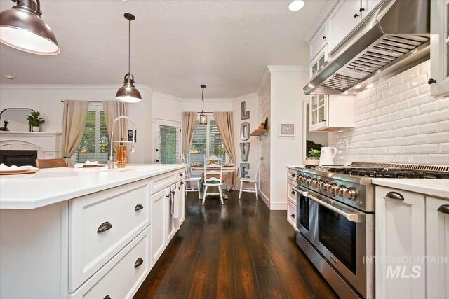 kitchen featuring range with two ovens, a sink, light countertops, ventilation hood, and pendant lighting