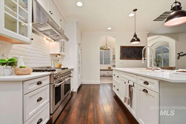 kitchen with double oven range, glass insert cabinets, ventilation hood, and light countertops