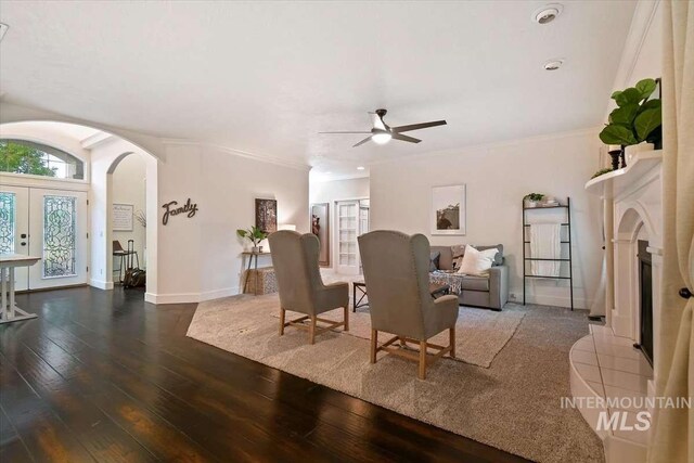 living area featuring baseboards, arched walkways, dark wood-style flooring, and ornamental molding