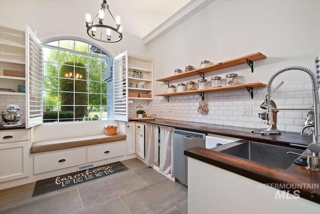 bar featuring a chandelier, light tile patterned floors, a sink, decorative backsplash, and dishwasher