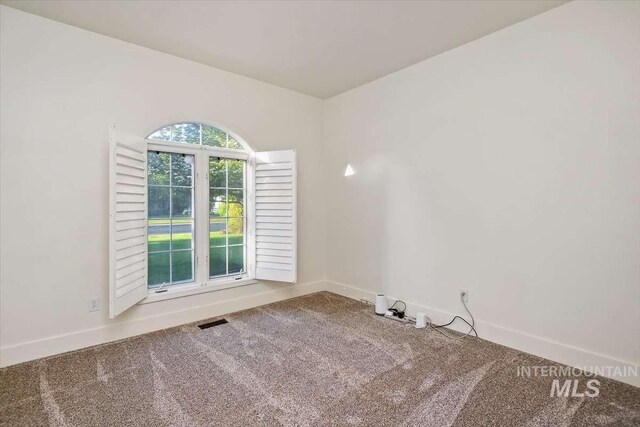 carpeted spare room featuring visible vents and baseboards