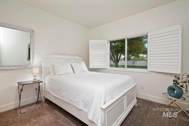 bedroom with dark carpet and baseboards