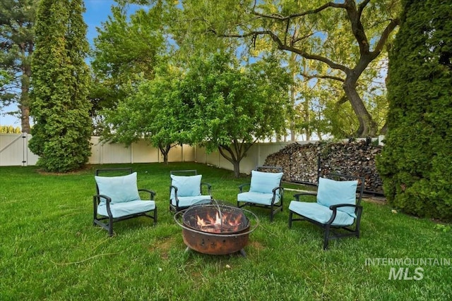 view of yard with a fire pit, a fenced backyard, and a gate