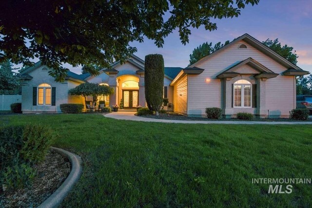 view of front facade with a lawn and french doors