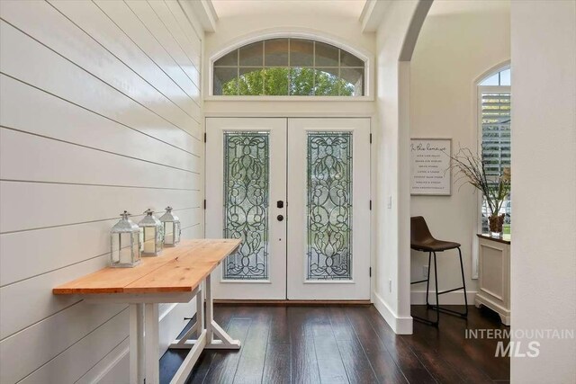 foyer entrance with arched walkways, french doors, and dark wood-style flooring