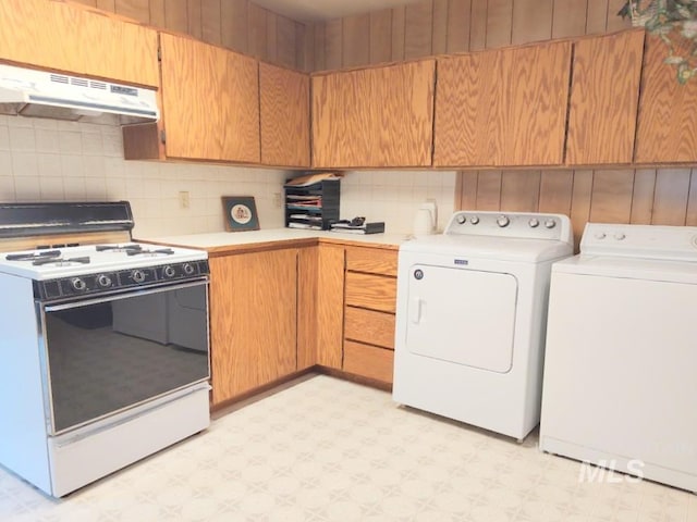 2738 Dixie Rd, Dixie, ID 83525 - kitchen with white electric stove, under cabinet range hood, light flooring, washing machine and clothes dryer, and decorative backsplash