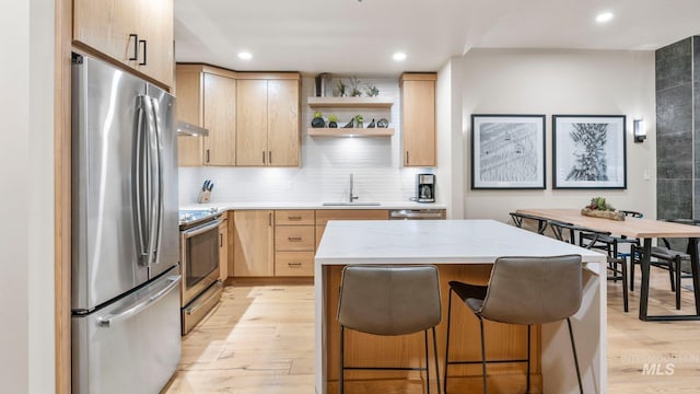 kitchen featuring a kitchen island, light brown cabinetry, light wood-type flooring, stainless steel appliances, and sink