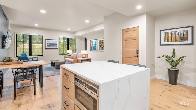 kitchen with light wood-type flooring, light brown cabinets, and a kitchen island