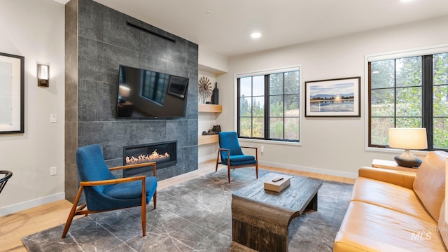 living room with a wealth of natural light, wood-type flooring, and a tile fireplace