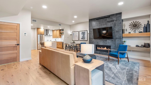 living room featuring a tiled fireplace and light hardwood / wood-style floors