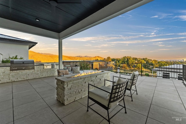 patio terrace at dusk with an outdoor fire pit, area for grilling, and a mountain view