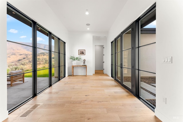 corridor with french doors, light hardwood / wood-style flooring, and a mountain view