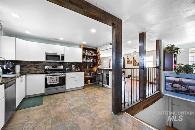 kitchen featuring backsplash, white cabinets, stainless steel appliances, and a textured ceiling