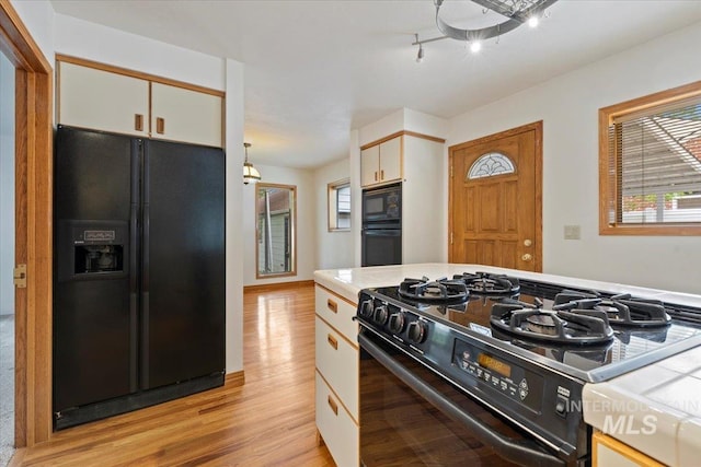 1915 N 23rd St, Boise, ID 83702 - kitchen featuring black appliances, plenty of natural light, white cabinets, and light wood-style flooring