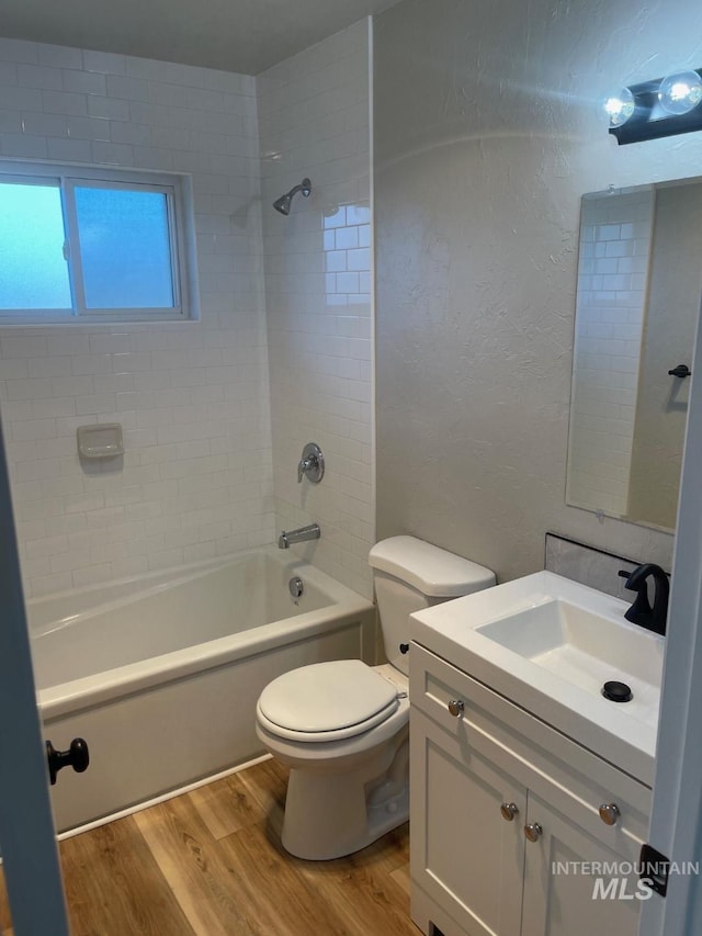 full bathroom with vanity, wood-type flooring, toilet, and tiled shower / bath