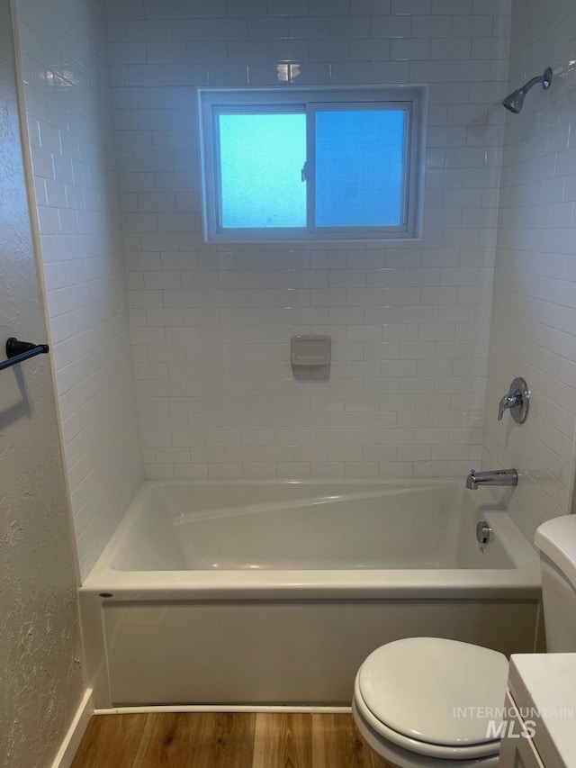 full bathroom with wood-type flooring, toilet, tiled shower / bath combo, and vanity