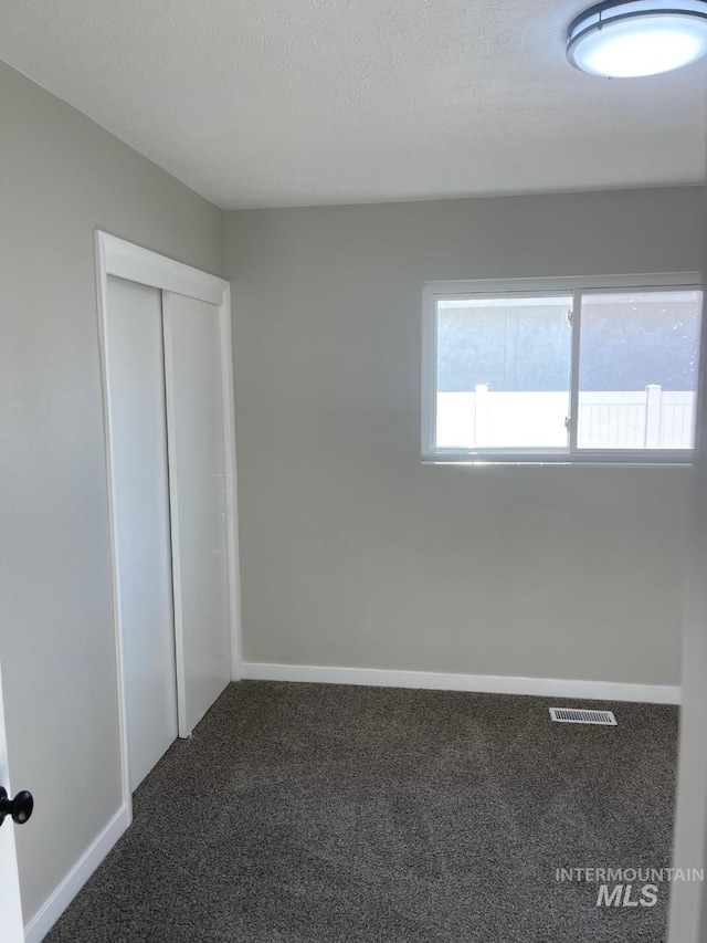 unfurnished bedroom featuring a closet, a textured ceiling, and carpet flooring