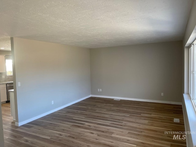 empty room with dark hardwood / wood-style flooring and a textured ceiling