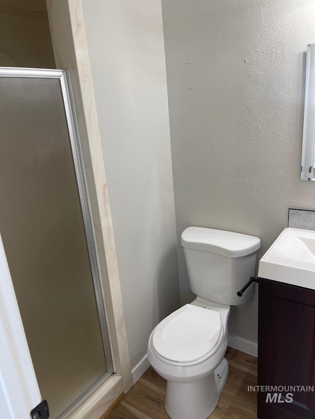 bathroom featuring hardwood / wood-style flooring, vanity, toilet, and walk in shower