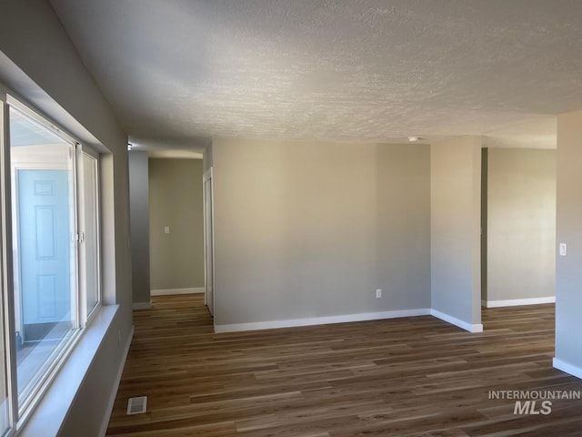 unfurnished room featuring dark hardwood / wood-style floors and a textured ceiling