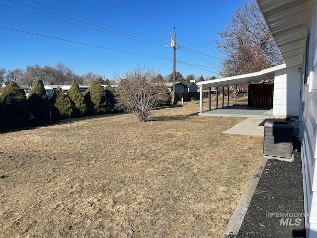 view of yard with a carport and central AC unit