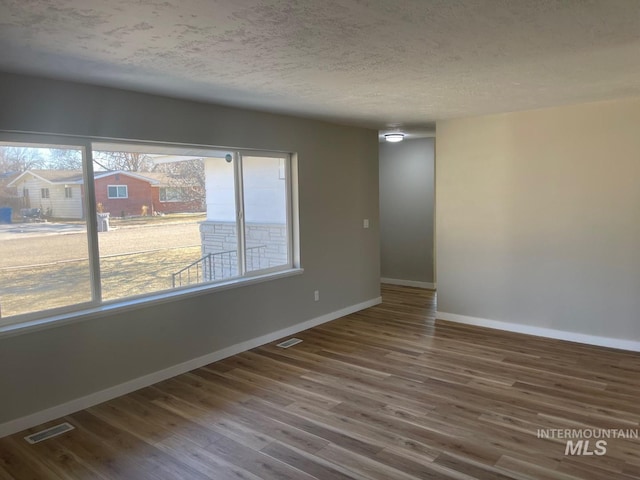 spare room with hardwood / wood-style floors, a wealth of natural light, and a textured ceiling