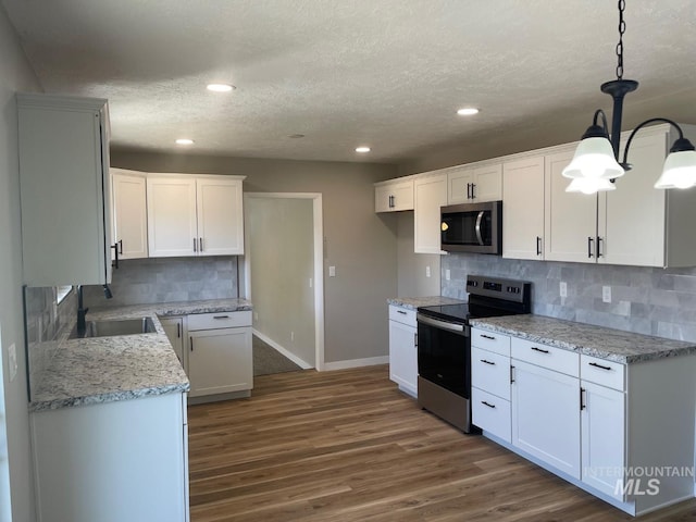 kitchen featuring decorative light fixtures, white cabinetry, sink, stainless steel appliances, and a textured ceiling