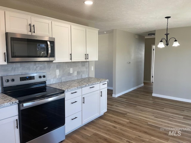 kitchen featuring appliances with stainless steel finishes, white cabinetry, backsplash, light stone countertops, and a textured ceiling