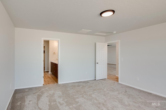 unfurnished bedroom featuring light carpet and connected bathroom