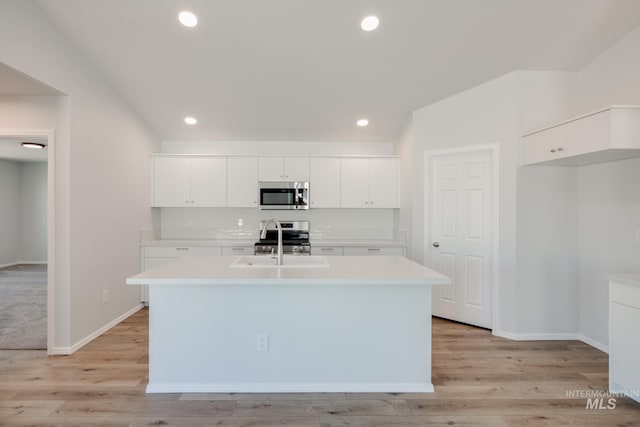 kitchen featuring white cabinets, sink, an island with sink, light hardwood / wood-style floors, and stainless steel appliances