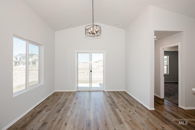 empty room featuring a wealth of natural light, lofted ceiling, and light wood-type flooring