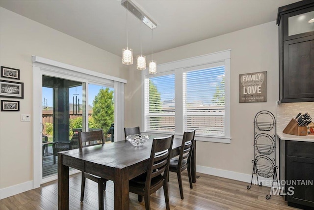 dining space with a wealth of natural light, hardwood / wood-style floors, and an inviting chandelier