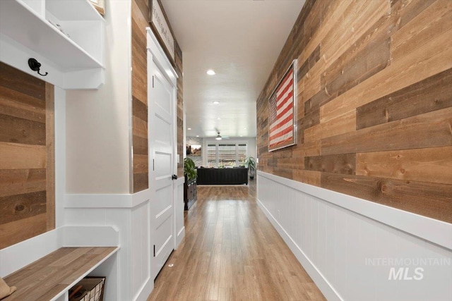 hall with wood walls and light hardwood / wood-style floors