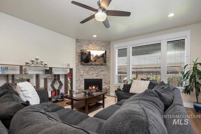 living room with hardwood / wood-style floors, a stone fireplace, and ceiling fan