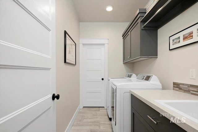 washroom with cabinets, separate washer and dryer, and light hardwood / wood-style flooring