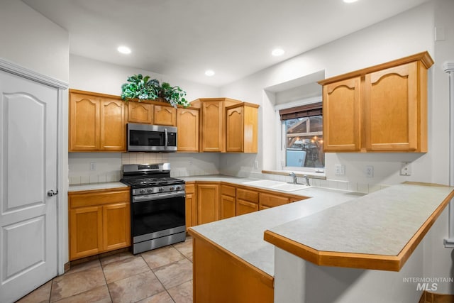 kitchen with light tile patterned flooring, sink, kitchen peninsula, and stainless steel appliances