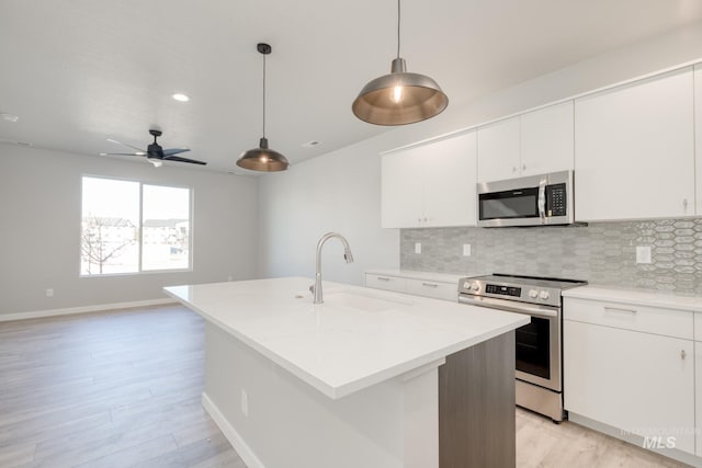 kitchen featuring appliances with stainless steel finishes, a kitchen island with sink, sink, and hanging light fixtures