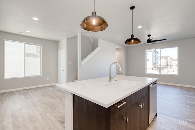 kitchen featuring sink, hanging light fixtures, dark brown cabinets, a center island with sink, and stainless steel dishwasher