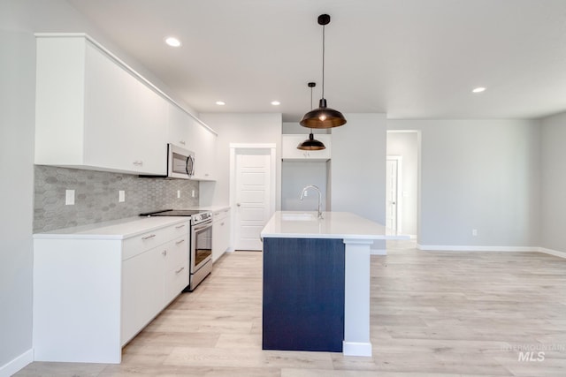 kitchen with pendant lighting, an island with sink, sink, white cabinets, and stainless steel appliances