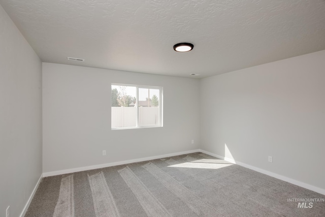 carpeted empty room with a textured ceiling